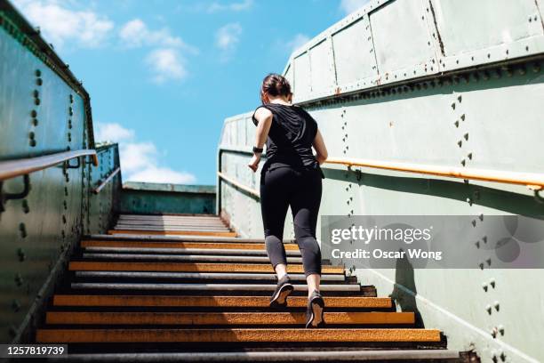 rear view of young woman running upstairs in art district, city downtown - london graffiti stock pictures, royalty-free photos & images