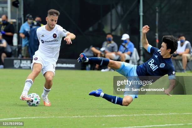 Hwang In-Beom of Vancouver Whitecaps attempts to tackle Alvaro Medran of Chicago Fire during a Group B match of the MLS Is Back Tournament at ESPN...