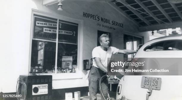 Man in t-shirt and jeans pumps gas at Hoppel's Mobile Service in Silver Lake, Los Angeles, circa 1947.