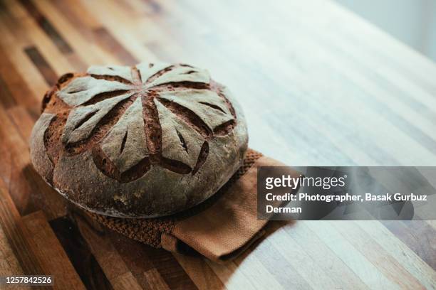 sourdough whole wheat bread on a kitchen towel - round loaf stock pictures, royalty-free photos & images