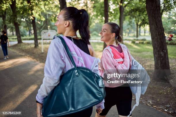 fröhliche junge athletinnen kehren vom training mit turntaschen zurück - sporttasche stock-fotos und bilder