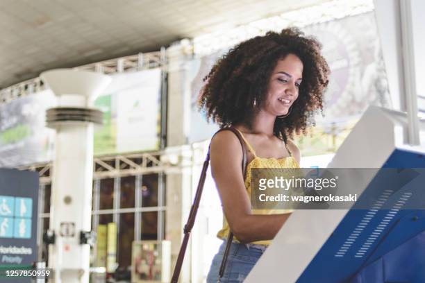 joven que usa el check-in de autoservicio en el aeropuerto - booth fotografías e imágenes de stock