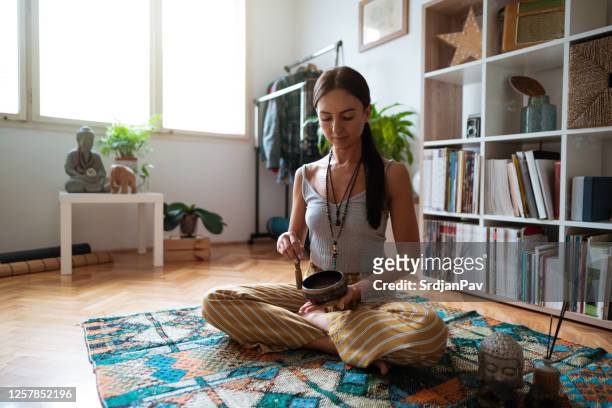 young woman and meditation bell sound therapy at home - feng shui house stock pictures, royalty-free photos & images