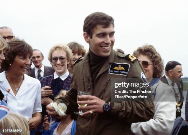 Prince Andrew wearing an aircrew uniform and drinking a glass of champagne amongst admirers at RNAS Culdrose in Helston, Cornwall after he and other...