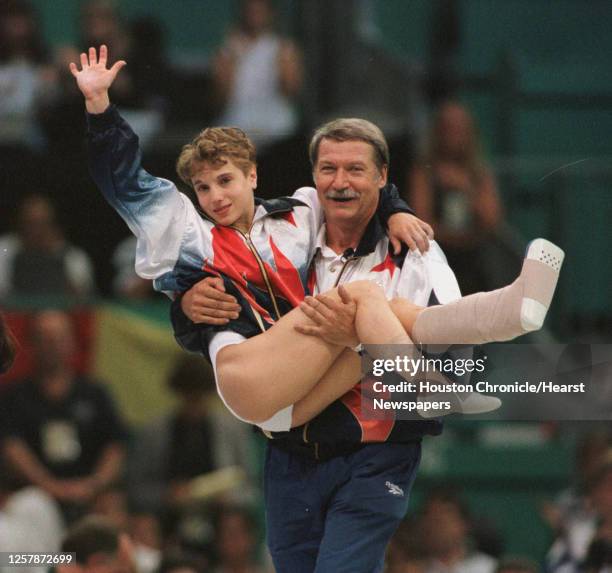 Coach Bela Karolyi carries the injured Kerri Strug to the medal ceremony after the US team win in artistic gymnastics. 1996 SUMMER OLYMPICS. HOUCHRON...