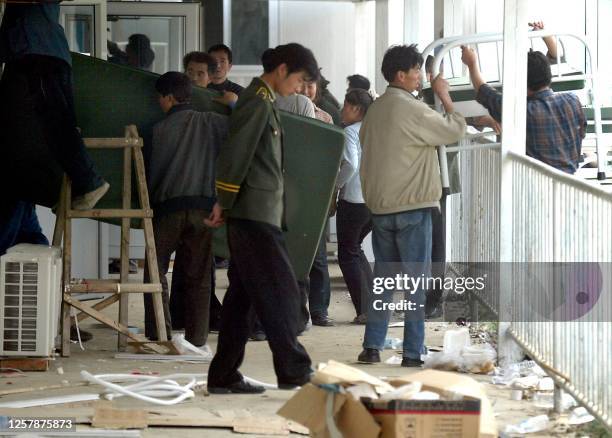 Workers bring in the bed and mattresses into a nearly completed ward at the hospital erected in barely a week to house a rapidly increasing number of...