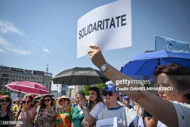 Romanian teacher holds up a sign reading 'solidarity' as she takes part in a protest in front of the Romanian Government headquarters in Bucharest on...