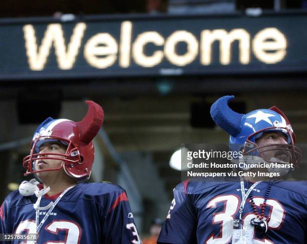 Texans fans Juan Chapa and his brother J.C. "Big Tex" Chapa gaze over the new stadium as a scoreboard sign flashes a welcome as the team practices at...