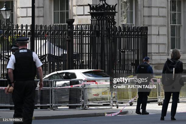 Police officers work near to a car, seen at the gates of Downing Street, on Whitehall in central London on May 25 after crashing into the front gates...