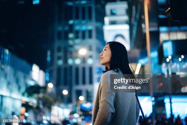 young asian female traveller enjoying holiday, exploring and strolling in downtown city street at night - city life night stock pictures, royalty-free photos & images