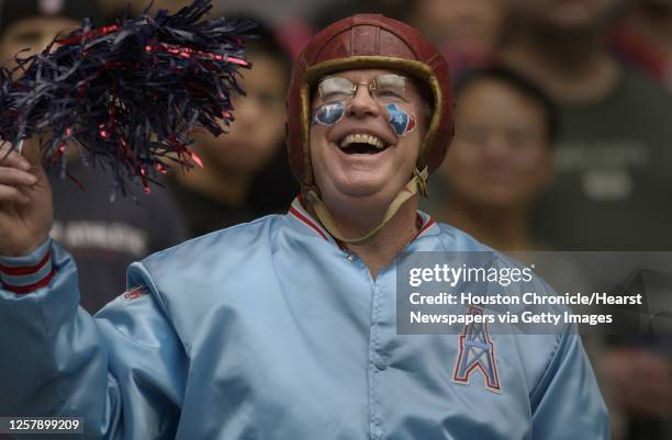 Texans fan Ron Hill wears a leather helmet, Oilers jacket, and face paintings of both the Titans and Texans logos as he cheers during pregame...