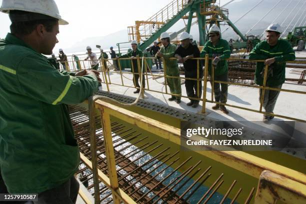 Construction workers look at the final piece of Greece's Rio-Antirio bridge while its put into place some 50 metres above sea level, completing basic...