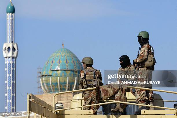Iraqi soldier secure the area as released Iraqi prisoners arrive ib four buses from the notorious Abu Ghraib prison west of the capital to the main...