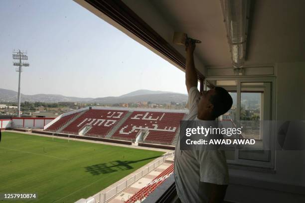 Worker paints a room 12 October 2005 inside the 13,000-capacity soccer stadium under construction in the northern Arab-Israeli town of Sakhnin,...