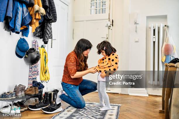 vrouw die jas draagt aan dochter - aankleden stockfoto's en -beelden