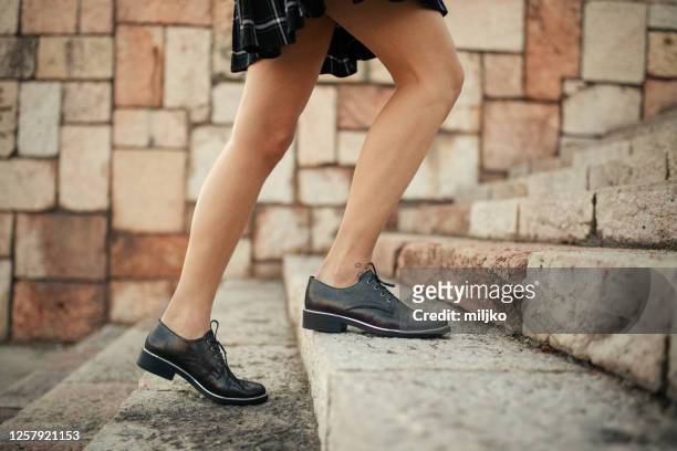 een onherkenbare jonge vrouw in een kleding beklimt de treden - uphill stockfoto's en -beelden