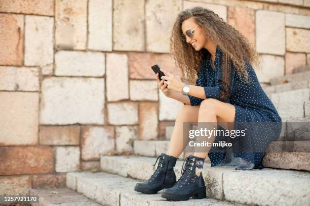 hermosa joven sentada en las escaleras - red boot fotografías e imágenes de stock