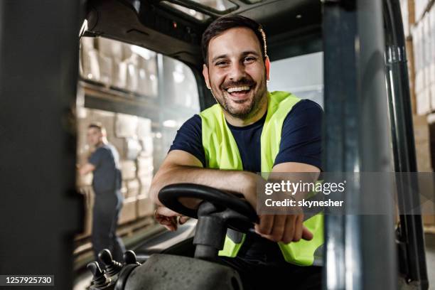 happy warehouse worker in a forklift at storage room. - forklift truck stock pictures, royalty-free photos & images