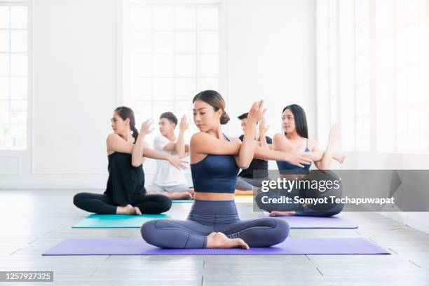 group of young asian people learning yoga class in fitness club female instructor with yoga class in the gym - mixed race man standing studio stockfoto's en -beelden