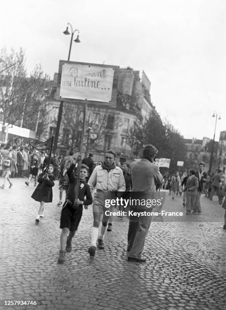 Enfant tenant une pancarte 'Maman ! Une tartine...' lors de la manifestation du 1er mai sur la place de la Bastille, à Paris, le 1er mai 1948, France.