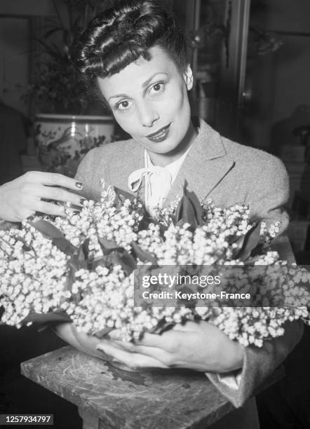 Jeune femme achetant des bouquets de muguet pour le 1er mai, à Paris, le 30 avril 1948, France.