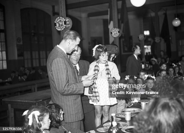 Le président du Conseil de Paris Pierre de Gaulle regardant l'étiquette d'une petite fille lors de son accueil des enfants sinistrés de Brest, avant...