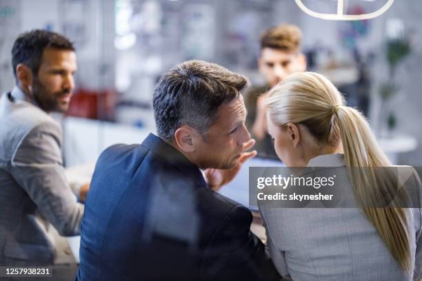 colleghi d'affari che spettegolano durante una riunione in ufficio. - sussurrare foto e immagini stock