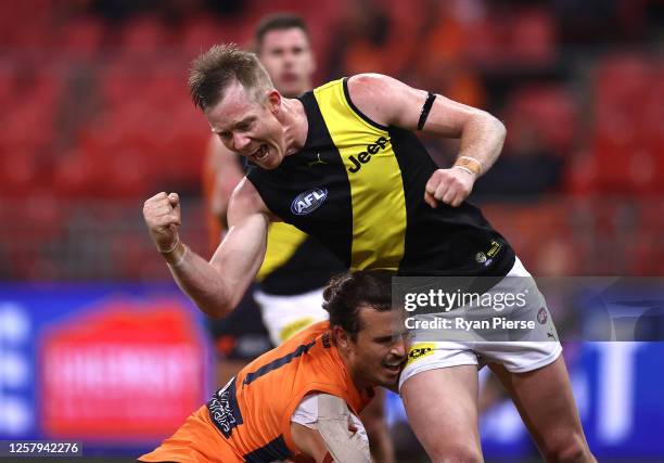 Jack Riewoldt of the Tigers celebrates a goal as Phil Davis of the Giants looks dejected during the round 8 AFL match between the Greater Western...