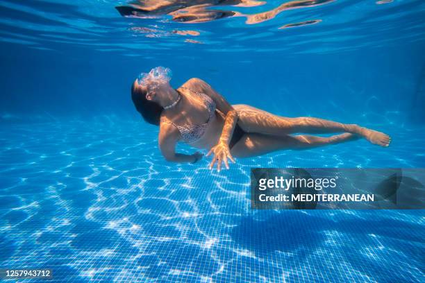 het meisje dat van de bikini onderwaterdans in een blauw tegelspool op de zomervakantie zwemt - girl diving stockfoto's en -beelden