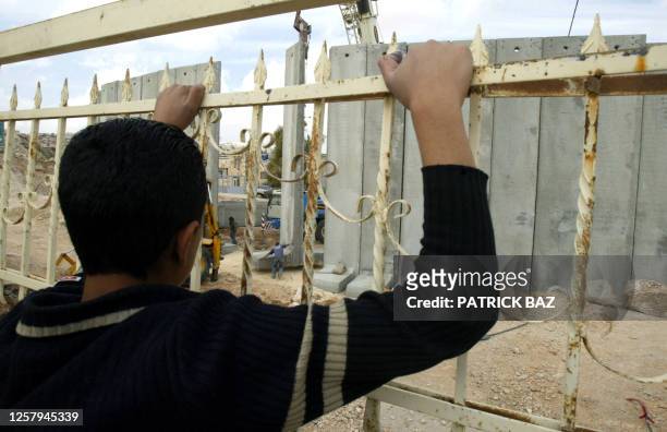 Grandson of Palestinian Abdul Aziz Shahadi Khatib looks through part of the fence in the back garden of their house partially destroyed by the...