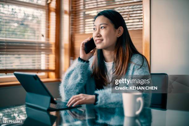 young asian woman using laptop working at home during covid-19 - new zealand business stock pictures, royalty-free photos & images