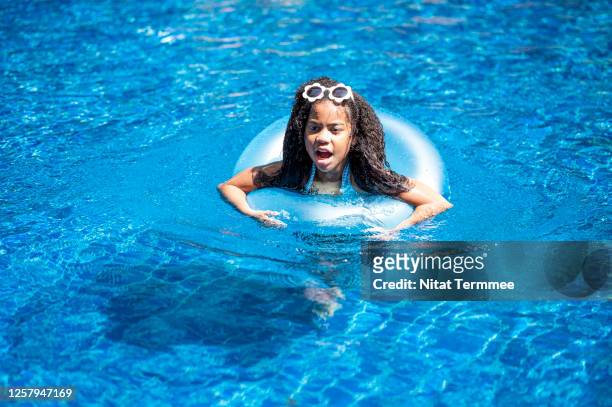 afro girl having fun in blue inflatable ring in swimming pool. - black girl swimsuit stock pictures, royalty-free photos & images