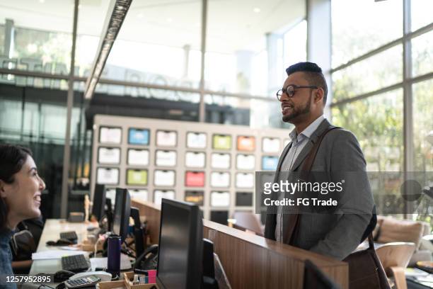 man in an office reception / lobby talking to a secretary - visit stock pictures, royalty-free photos & images