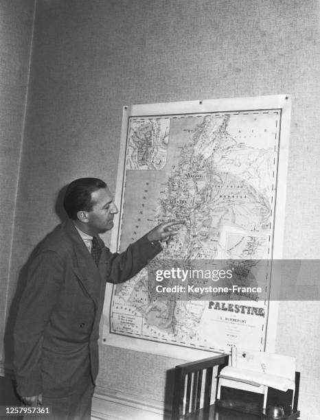 Un homme montre une carte murale de la Palestine punaisée à un mur de l'Agence juive pour la Palestine, à Paris, France le 14 mai 1948 après...