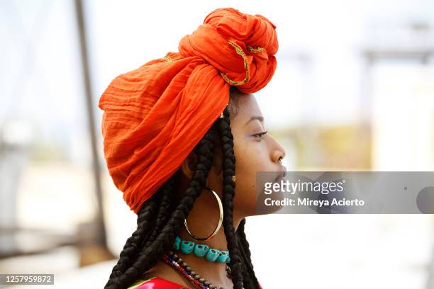 portrait of a beautiful african american woman wearing an orange head scarf, beaded necklaces and long dreads in an outdoor setting. - tradition stock pictures, royalty-free photos & images