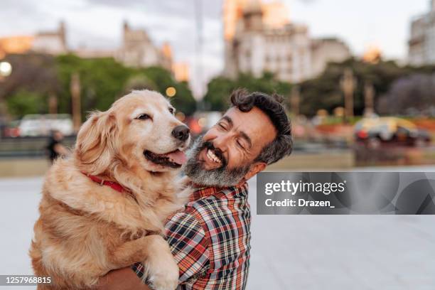 hogere latino mens die zijn hogere hond van retriever koestert - middle age man with dog stockfoto's en -beelden