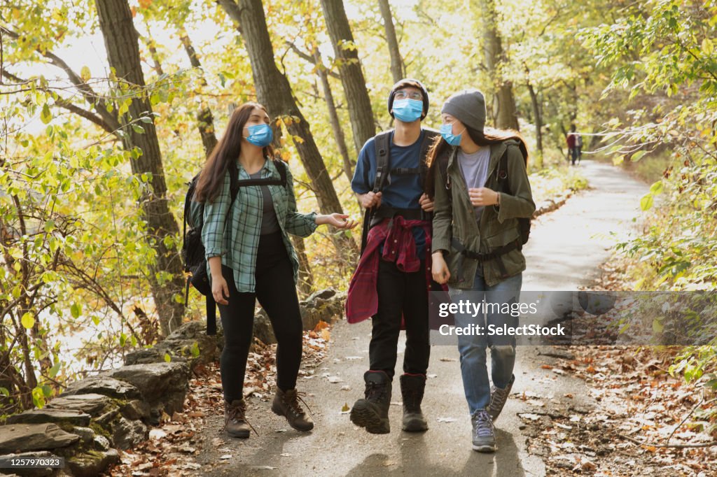 Teenager friends hiking outside in nature wearing mask