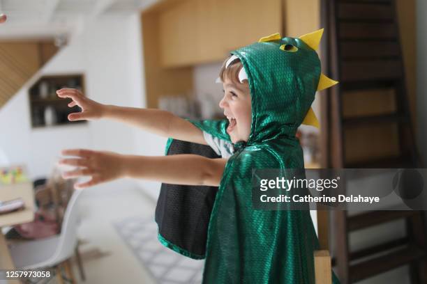 a little boy dressed as a dinosaur playing in the kitchen - france costume stockfoto's en -beelden