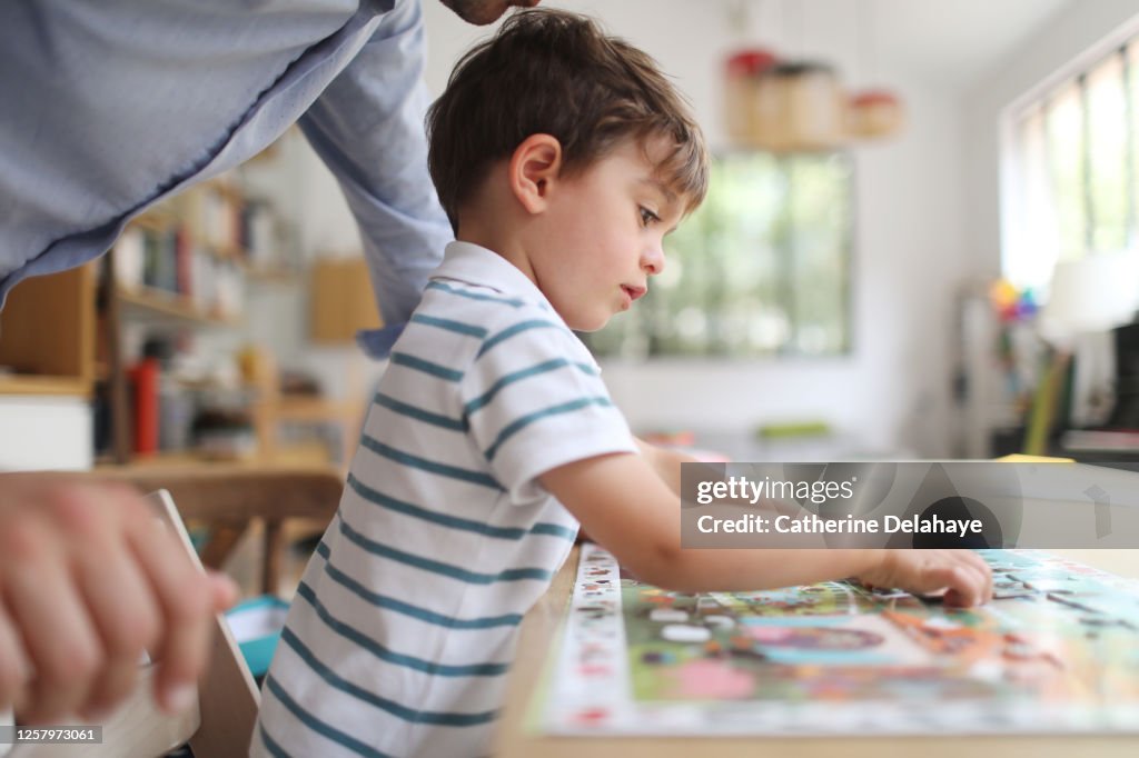 A 4 year old boy making a puzzle with his dad