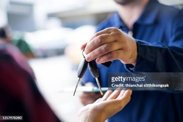 car repairman giving car keys to customer - dar fotografías e imágenes de stock