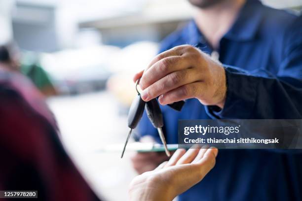 car repairman giving car keys to customer - stand de carros imagens e fotografias de stock