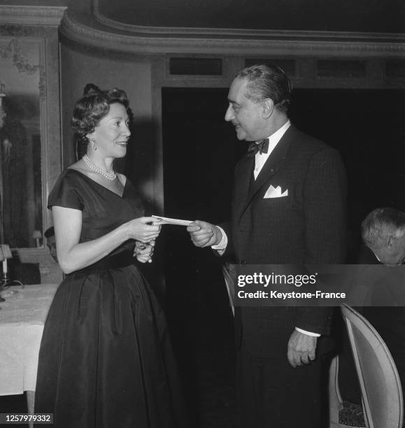 Madame Amar remet le chèque au lauréat Jacques-Charles pour son livre 'Cent ans de music-hall', à Paris, France le 22 février 1957.