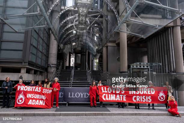 Climate activists wearing red boiler suits and letting off flares protest outside the Lloyd's building in the City of London while the Lloyds Annual...