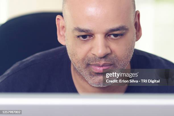 middle aged black man looking closely at his computer activities - looking closely stock pictures, royalty-free photos & images