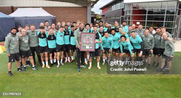 Jurgen Klopp manager of Liverpool presents Adam Lallana of Liverpool with a pictures because he is leaving Liverpool F C before a training session at...