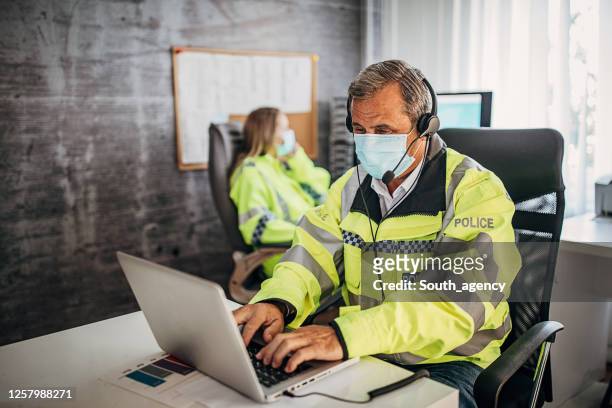 one senior police officer working on laptop in police office - funcionário público imagens e fotografias de stock