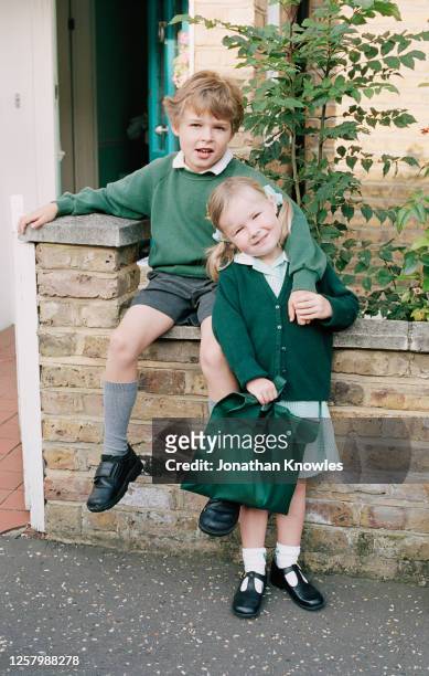 brother and sister in school uniforms - groene schoen stockfoto's en -beelden