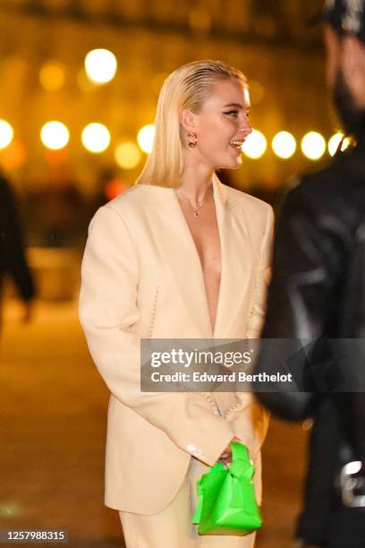 Zara Larson wears, a beige oversized blazer jacket, a neon green bag, earrings, outside Acne, during Paris Fashion Week - Menswear Fall/Winter...