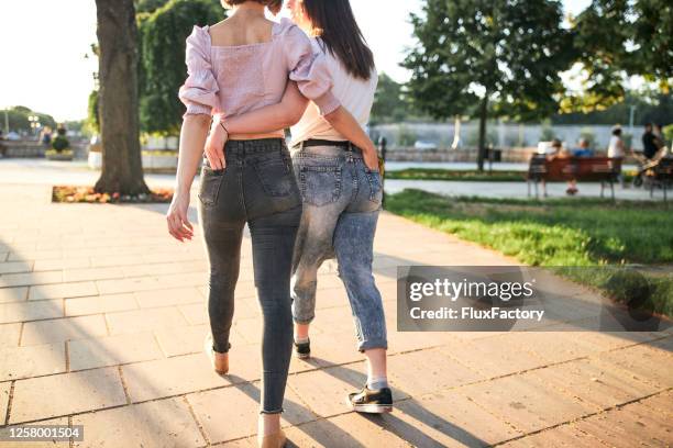 jeune couple mignon de lesbienne marchant avec des mains dans les poches arrière de l’autre dans la ville - back pocket photos et images de collection