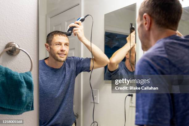 man giving himself a haircut at home - homme coiffure photos et images de collection